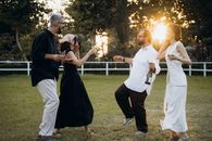 Group of friends dancing and enjoying a summer evening outdoors with drinks in hand.